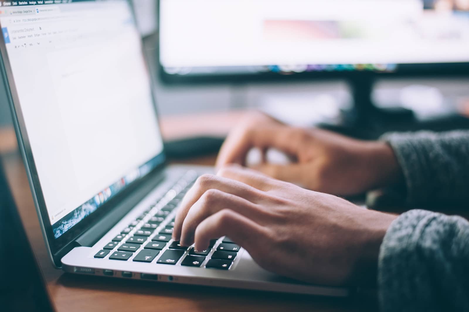 photo of person writing faster on a  laptop